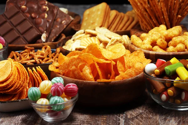 Snacks salados. Pretzels, papas fritas, galletas en cuencos de madera en la mesa —  Fotos de Stock