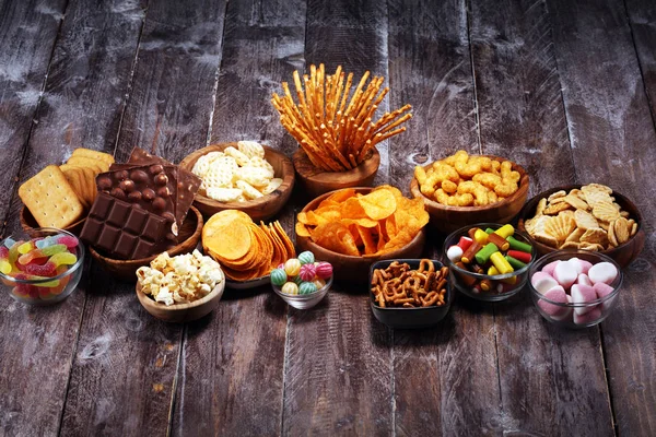 Petiscos salgados. Pretzels, batatas fritas, biscoitos em tigelas de madeira na mesa — Fotografia de Stock