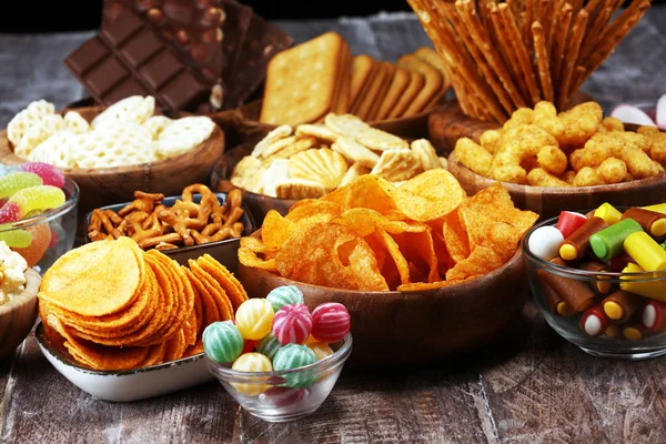Petiscos salgados. Pretzels, batatas fritas, biscoitos em tigelas de madeira na mesa — Fotografia de Stock