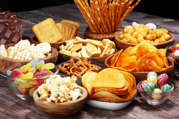 Salty snacks. Pretzels, chips, crackers in wooden bowls on table