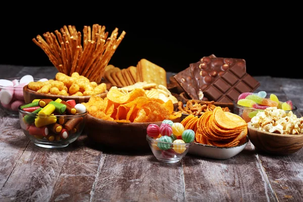 Snacks salados. Pretzels, papas fritas, galletas en cuencos de madera en la mesa — Foto de Stock