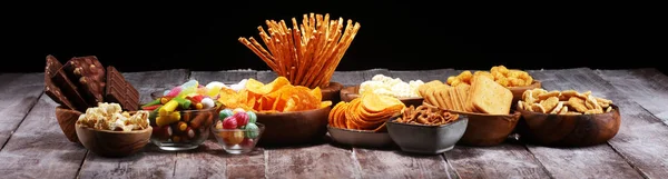 Snacks salados. Pretzels, papas fritas, galletas en cuencos de madera en la mesa — Foto de Stock