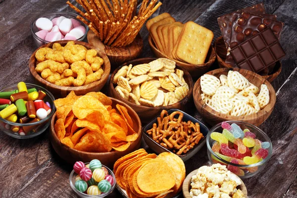 Petiscos salgados. Pretzels, batatas fritas, biscoitos em tigelas de madeira na mesa — Fotografia de Stock