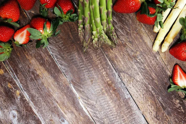 Espargos brancos e verdes com morangos em madeira — Fotografia de Stock