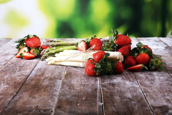Espargos brancos e verdes com morangos em madeira — Fotografia de Stock