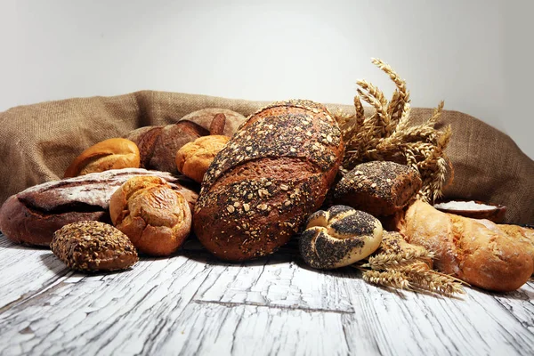 Assortiment van gebakken brood en broodjes op rustieke witte bakkerij — Stockfoto