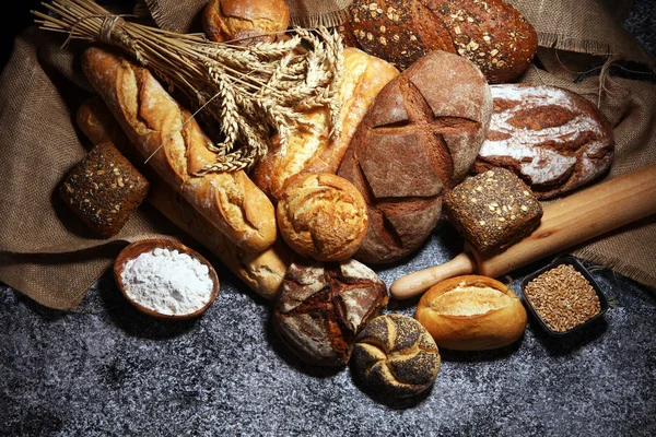 Assortiment van gebakken brood en broodjes op rustieke grijze bakkerij — Stockfoto