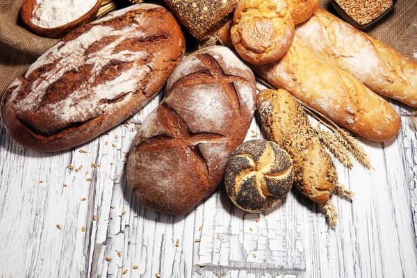 Sortiment aus gebackenem Brot und Brötchen auf rustikaler Weißbäckerei — Stockfoto