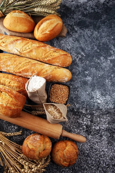 Assortment of baked bread and bread rolls on rustic grey bakery — Stock Photo, Image