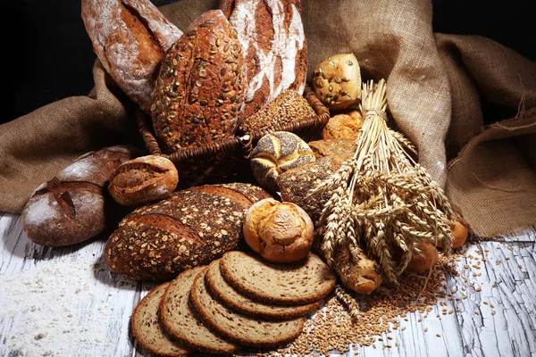 Assortiment de pains cuits au four et petits pains sur une boulangerie rustique blanche — Photo