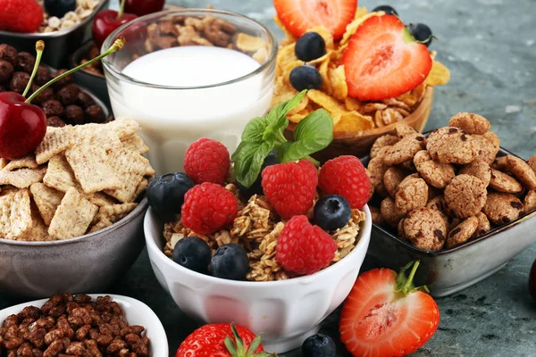 Cereales. Tazones de diversos cereales, bayas y leche para el desayuno —  Fotos de Stock