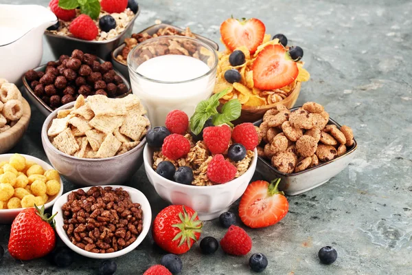 Cereales. Tazones de diversos cereales, bayas y leche para el desayuno —  Fotos de Stock