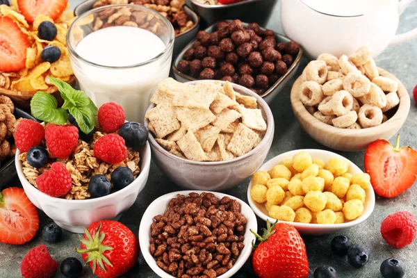 Cereales. Tazones de diversos cereales, bayas y leche para el desayuno —  Fotos de Stock