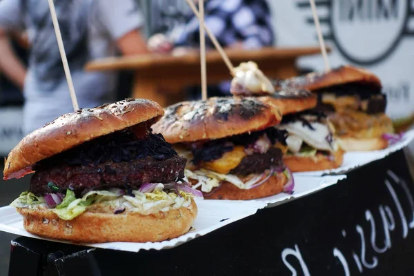 Szerves Burger az utcai élelmiszer-fesztivál a kezében. Zsíros sertés vagy b — Stock Fotó