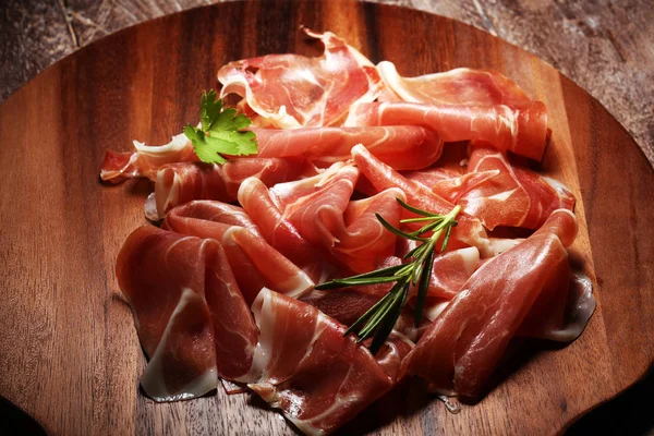 Italiensk prosciutto crudo eller jamon med rosmarin. Rå skinka på trä — Stockfoto