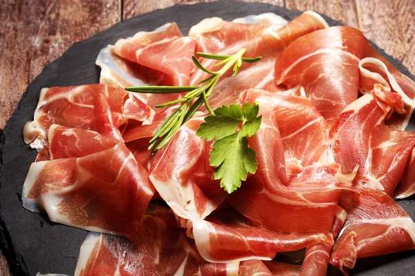 Prosciutto crudo italiano o jamón con romero. Jamón crudo sobre madera —  Fotos de Stock