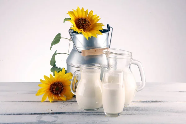 Глечик молока і склянка молока на дерев'яному столі і квітці — стокове фото