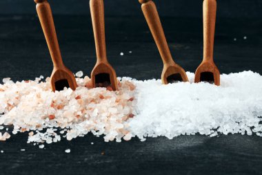 Kaşıkta deniz tuzu ve himalaya. Koyu backgr üzerinde tuz kristalleri