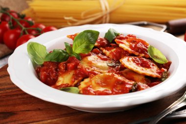 Mantı domates soslu parmesan peyniri ve bas ile süslenmiş