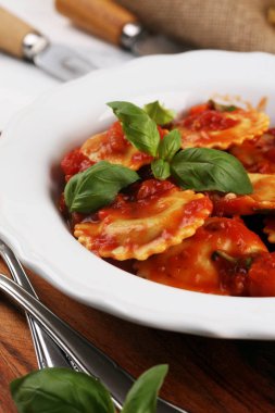 Mantı domates soslu parmesan peyniri ve bas ile süslenmiş