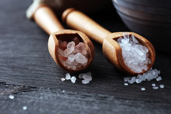 Kaşıkta deniz tuzu ve himalaya. Koyu backgr üzerinde tuz kristalleri