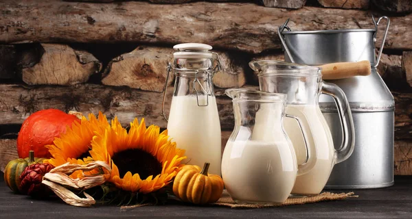 Глечик молока і склянка молока на дерев'яному столі і квітці — стокове фото