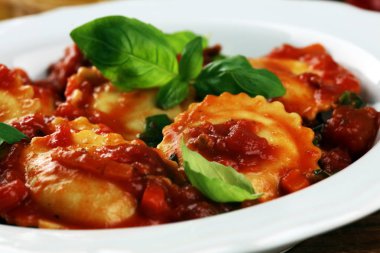 Mantı domates soslu parmesan peyniri ve bas ile süslenmiş