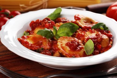 Mantı domates soslu parmesan peyniri ve bas ile süslenmiş