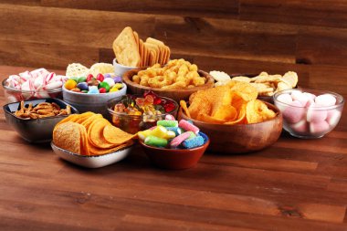 Tuzlu atıştırmalıklar. Tabl üzerinde kraker, cips, kraker ve şeker tatlılar