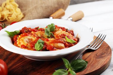 Mantı domates soslu parmesan peyniri ve bas ile süslenmiş