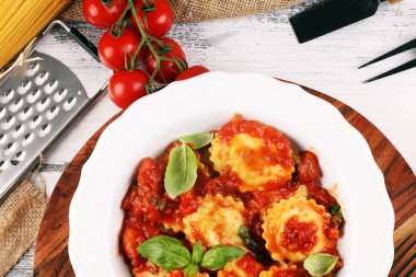 Mantı domates soslu parmesan peyniri ve bas ile süslenmiş