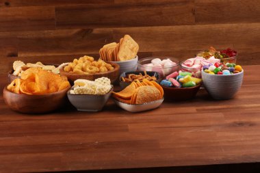 Tuzlu atıştırmalıklar. Tabl üzerinde kraker, cips, kraker ve şeker tatlılar