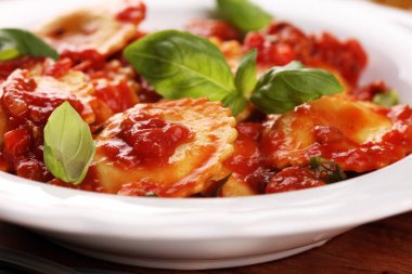 Mantı domates soslu parmesan peyniri ve bas ile süslenmiş