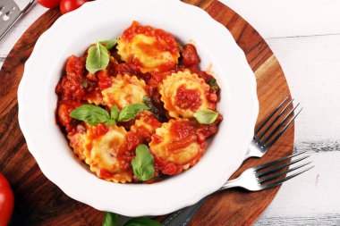 Mantı domates soslu parmesan peyniri ve bas ile süslenmiş