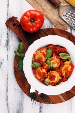 Mantı domates soslu parmesan peyniri ve bas ile süslenmiş