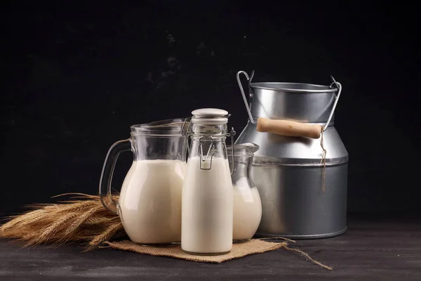 Ein Krug Milch und ein Glas Milch auf einem schwarzen Holztisch — Stockfoto