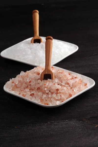 Sea salt and himalayan in bowl. Crystals of salt on dark backgro