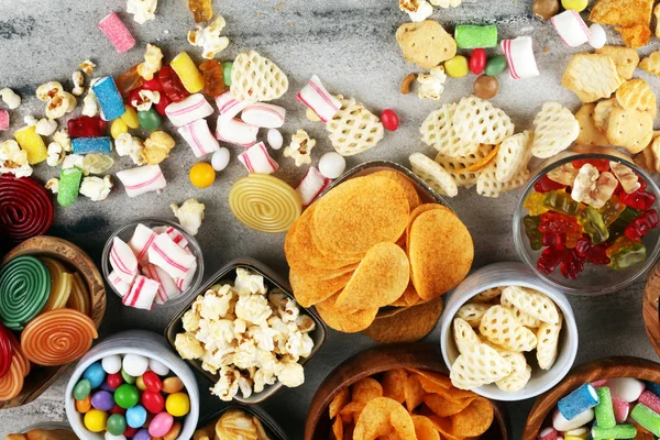 Petiscos salgados. Pretzels, batatas fritas, biscoitos e doces na mesa — Fotografia de Stock