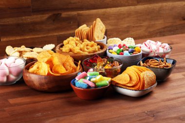 Tuzlu atıştırmalıklar. Tabl üzerinde kraker, cips, kraker ve şeker tatlılar