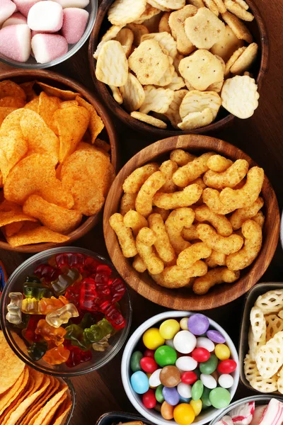 Salty snacks. Pretzels, chips, crackers and candy sweets on tabl — Stock Photo, Image