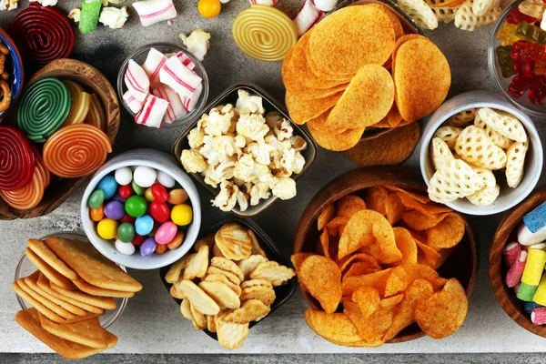 Petiscos salgados. Pretzels, batatas fritas, biscoitos e doces na mesa — Fotografia de Stock