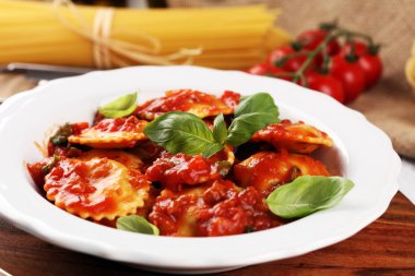 Mantı domates soslu parmesan peyniri ve bas ile süslenmiş