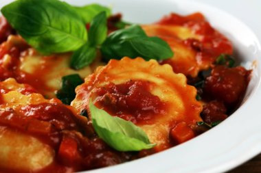 Mantı domates soslu parmesan peyniri ve bas ile süslenmiş