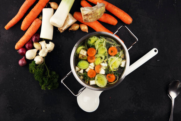 Broth with carrots, onions various fresh vegetables in a pot - c