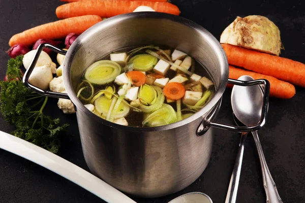 Bouillon met wortelen, uien diverse verse groenten in een pot - c — Stockfoto