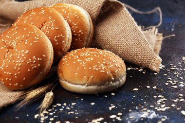 Koyu arkaplanda susamlı ev yapımı hamburger çörekleri.