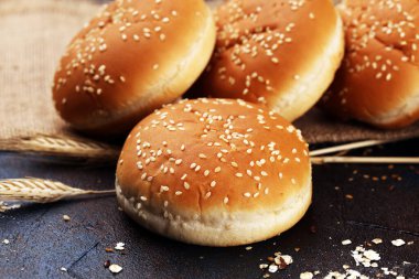 Koyu arkaplanda susamlı ev yapımı hamburger çörekleri.
