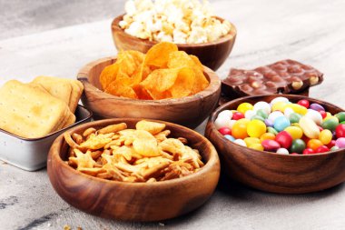 Salty snacks. Pretzels, chips, crackers in wooden bowls and cand clipart