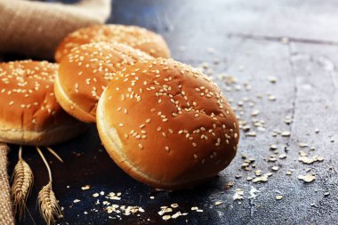 Koyu arkaplanda susamlı ev yapımı hamburger çörekleri.
