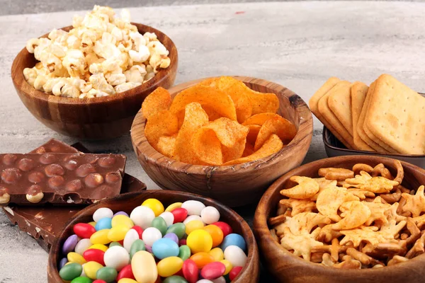 Salty snacks. Pretzels, chips, crackers in wooden bowls and cand — Stock Photo, Image